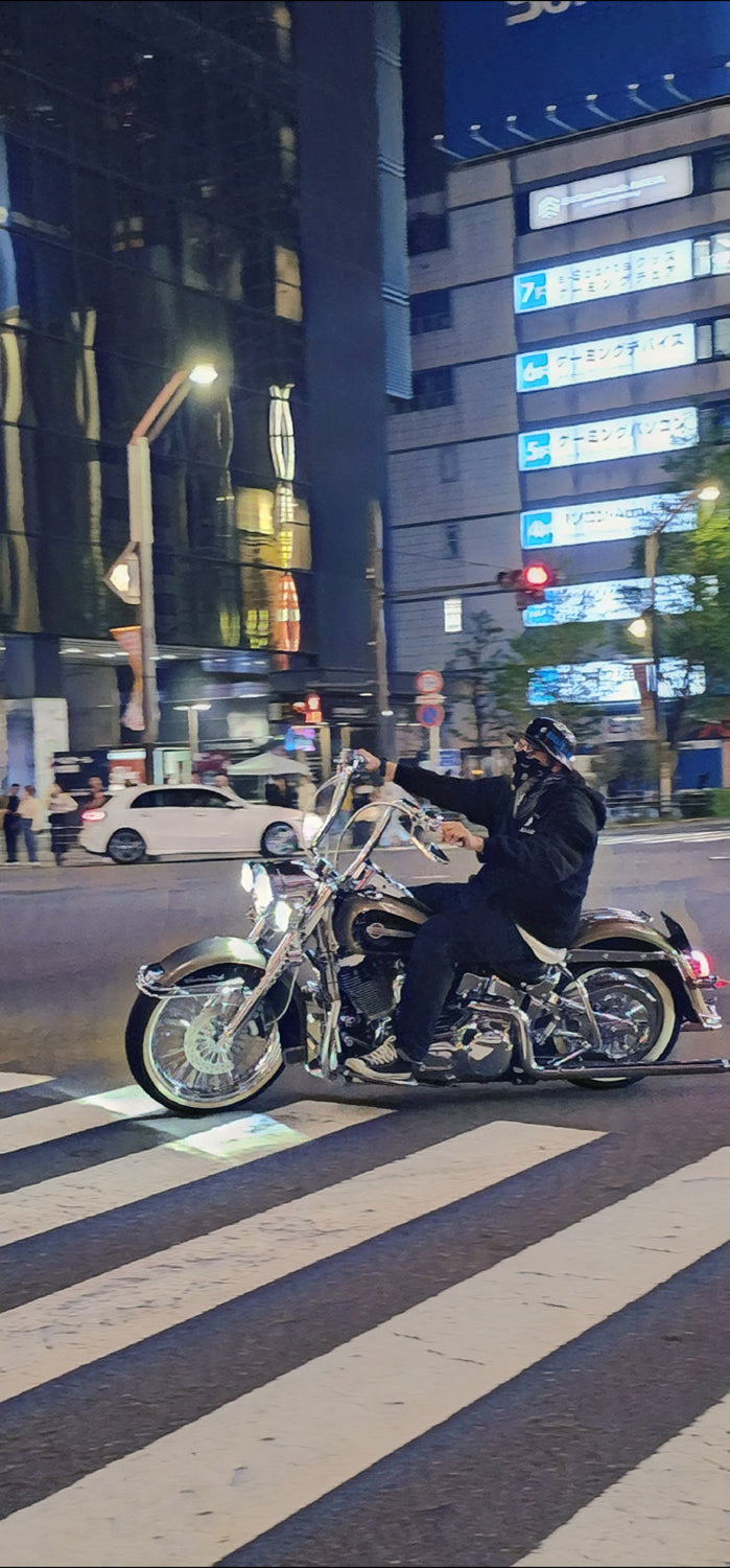 Person riding a motorcycle on a city street at night with illuminated signs and lights.