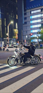 Person riding a motorcycle on a city street at night with illuminated signs and lights.